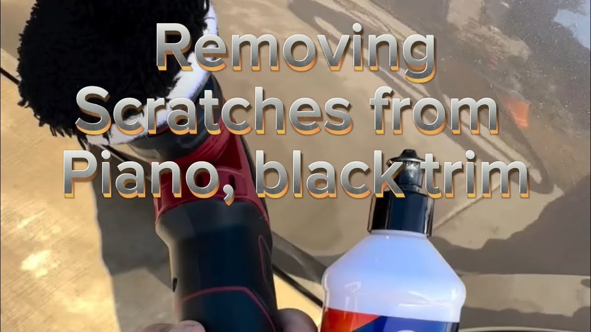 A hand polishing a scratched piano black car interior trim panel with a microfiber cloth.